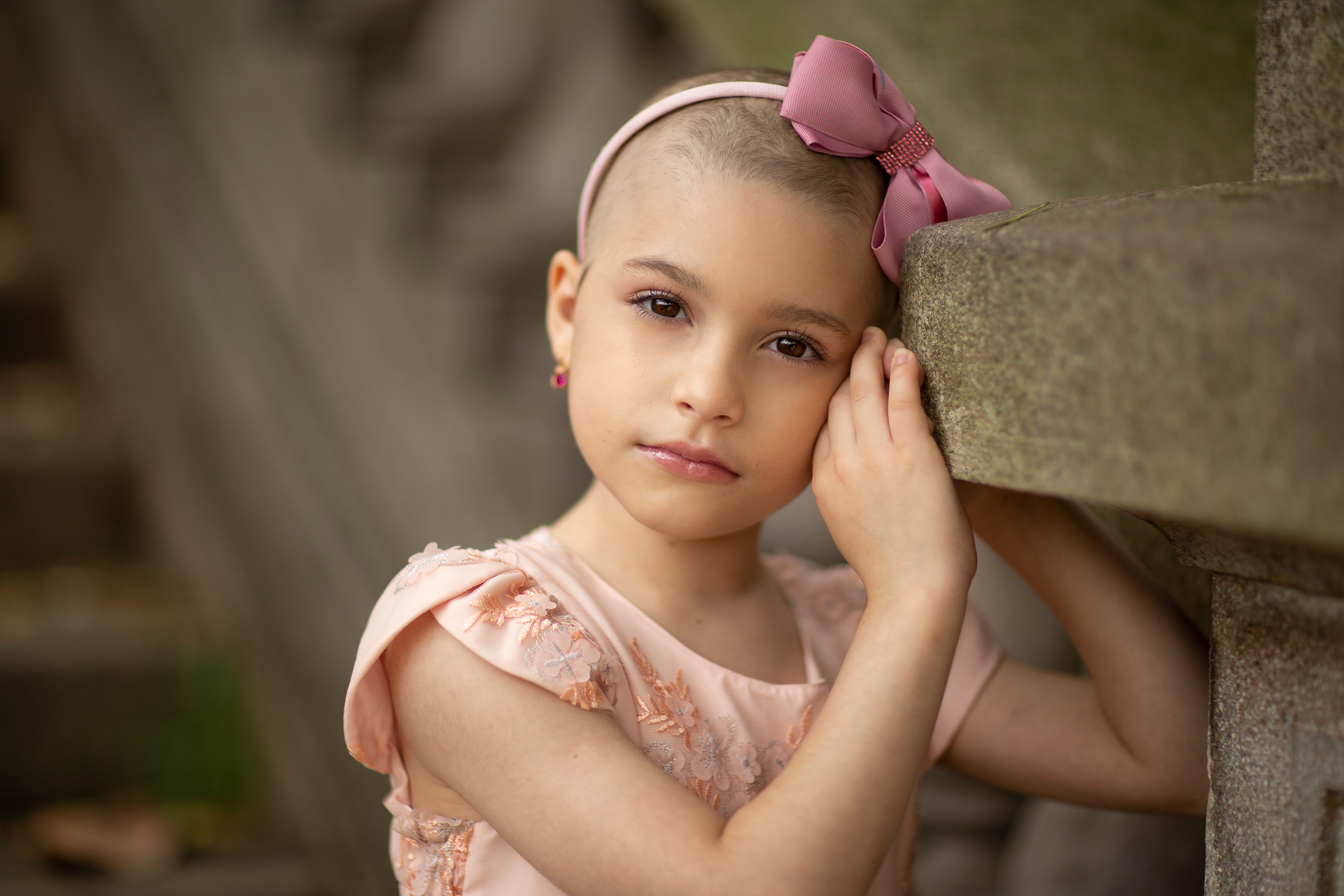 Charming girl in headband leaning on stone surface
