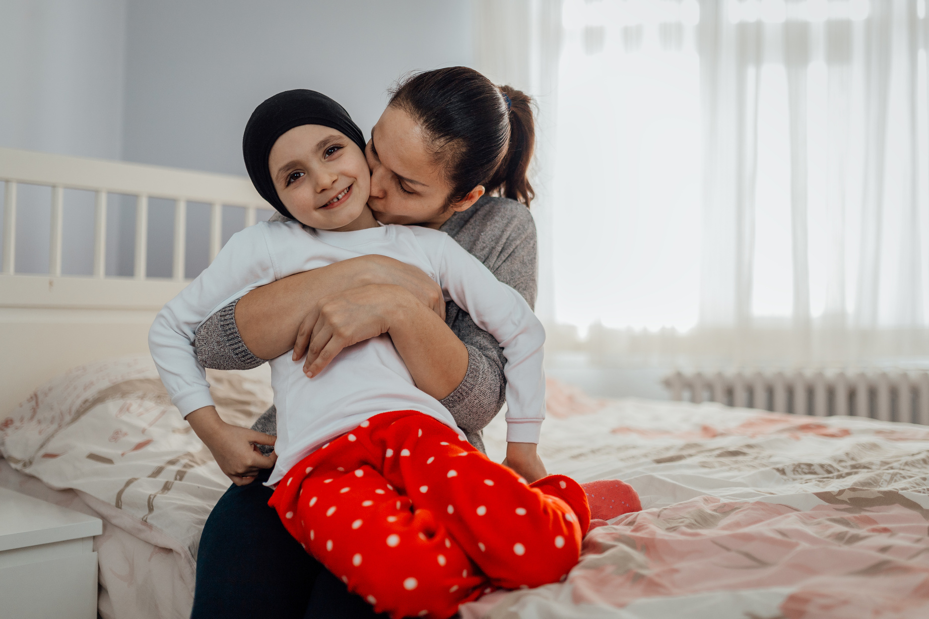 mother hugs and kisses her child with cancer